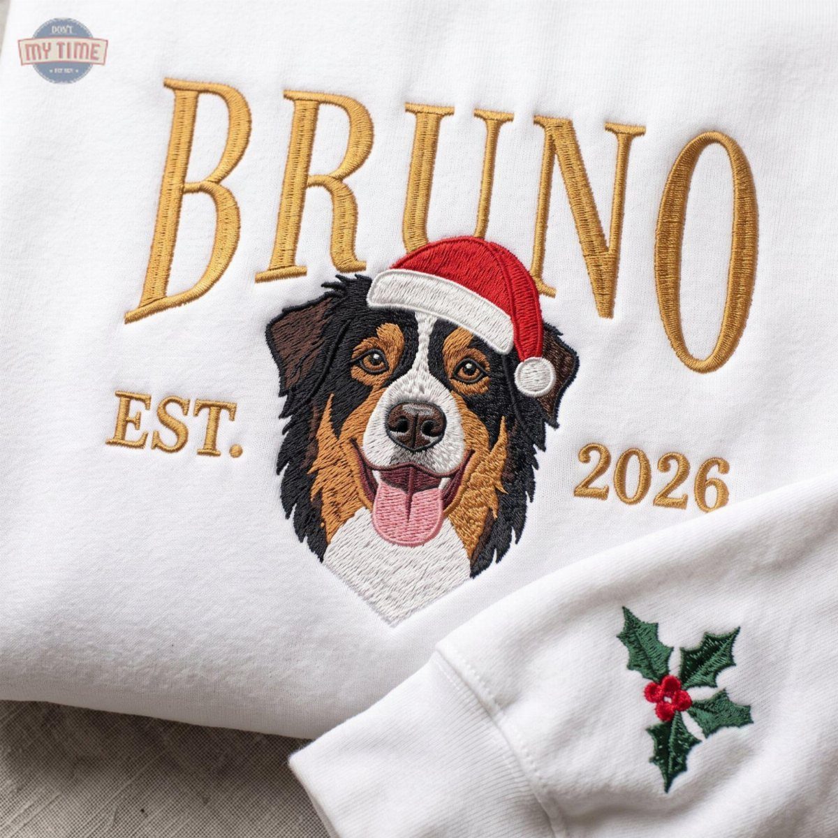 White sweatshirt with embroidered dog portrait wearing a Santa hat and gold text.