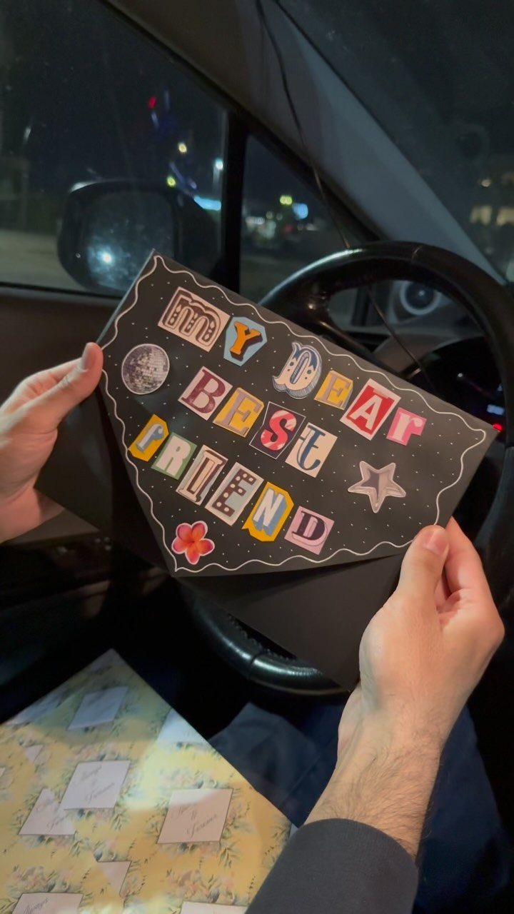 Handmade black card with colorful lettering saying My Dear Best Friend held in a car.