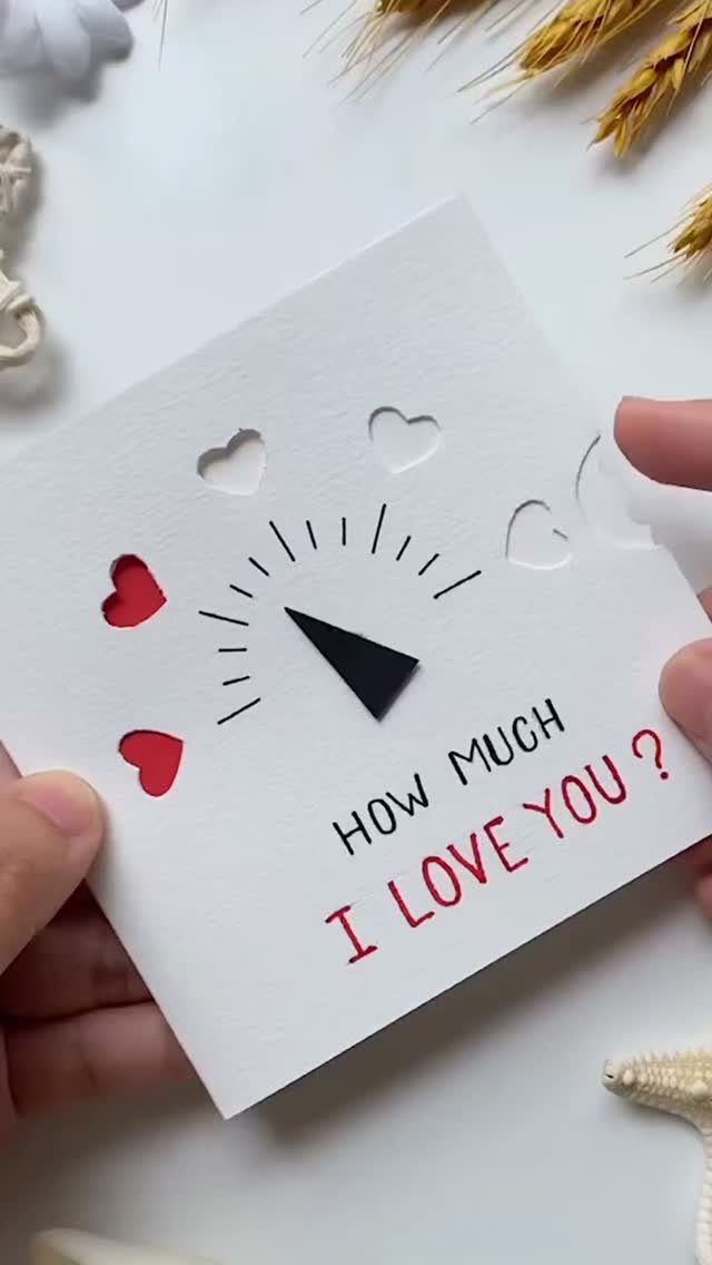 Handmade white love card with a moving needle and heart cutouts.
