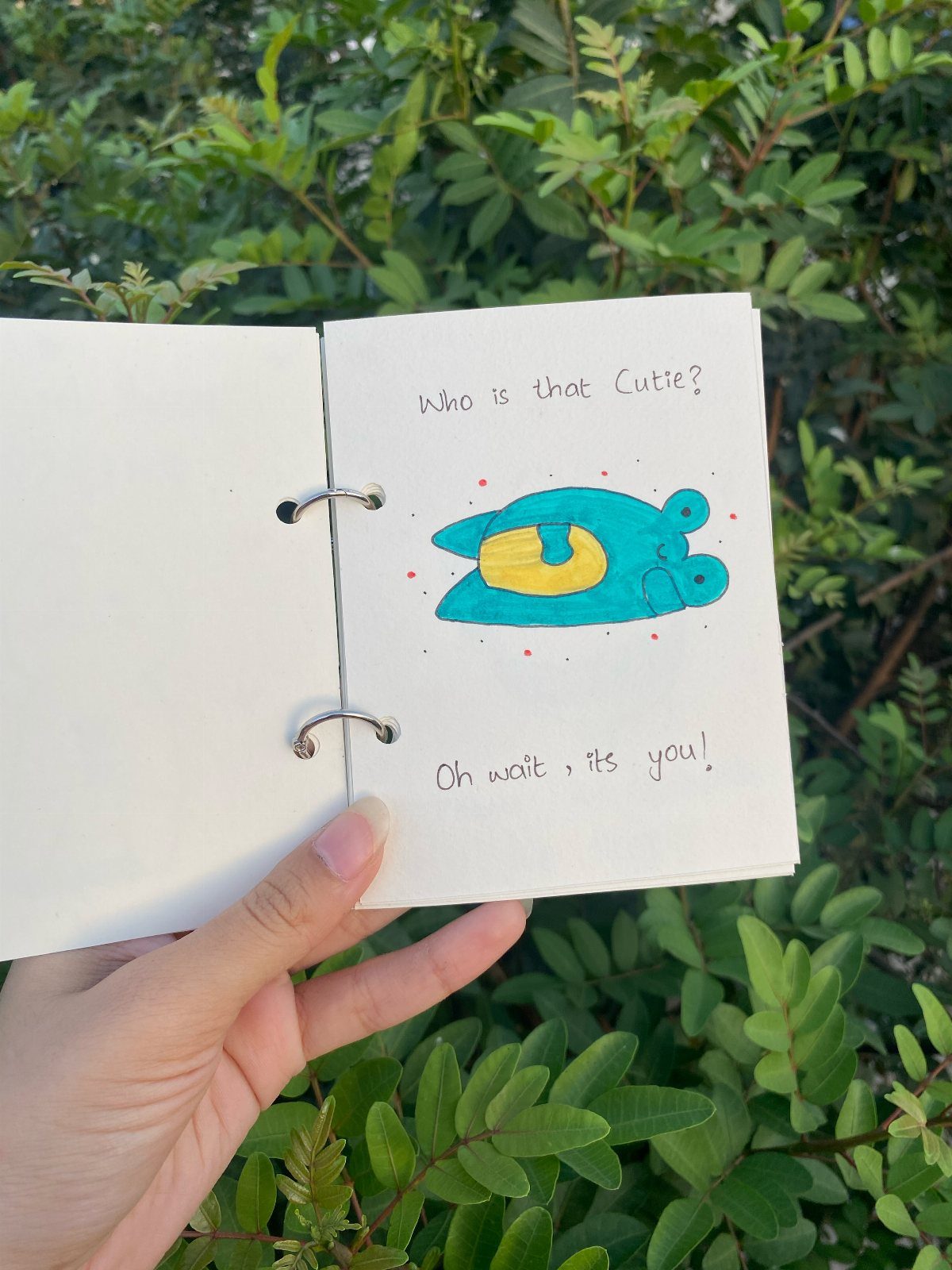 Handmade ring-bound book with a cute blue drawing and handwritten romantic message.