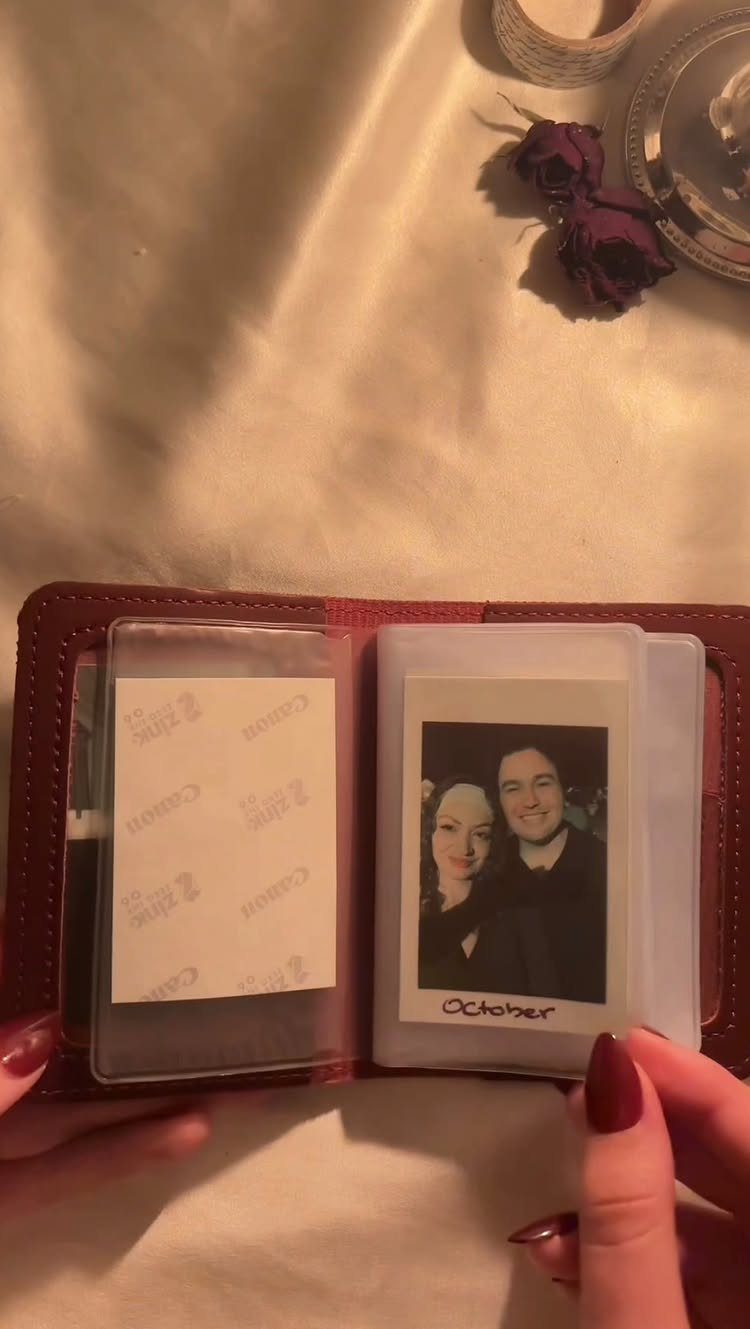 Red leather wallet holding a small Polaroid photo of a smiling couple.