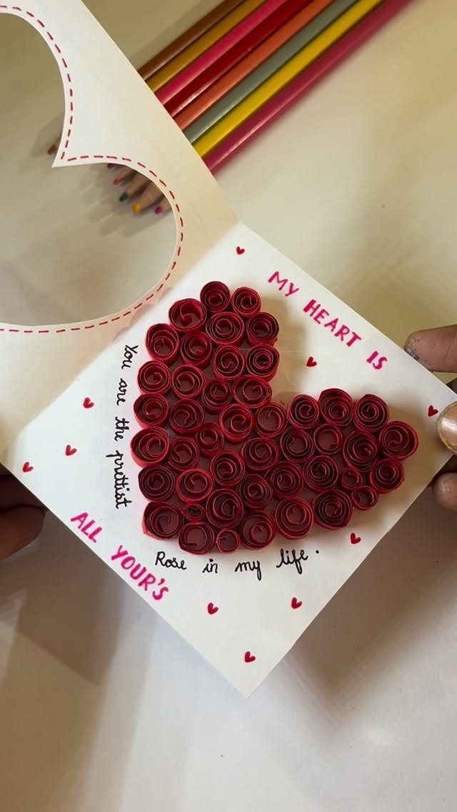 Handmade white card with a heart made of red paper roses and handwritten text.