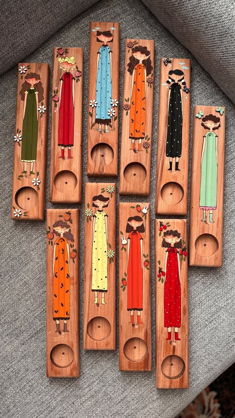 Wooden incense holders featuring colorful painted illustrations of women in various dresses.