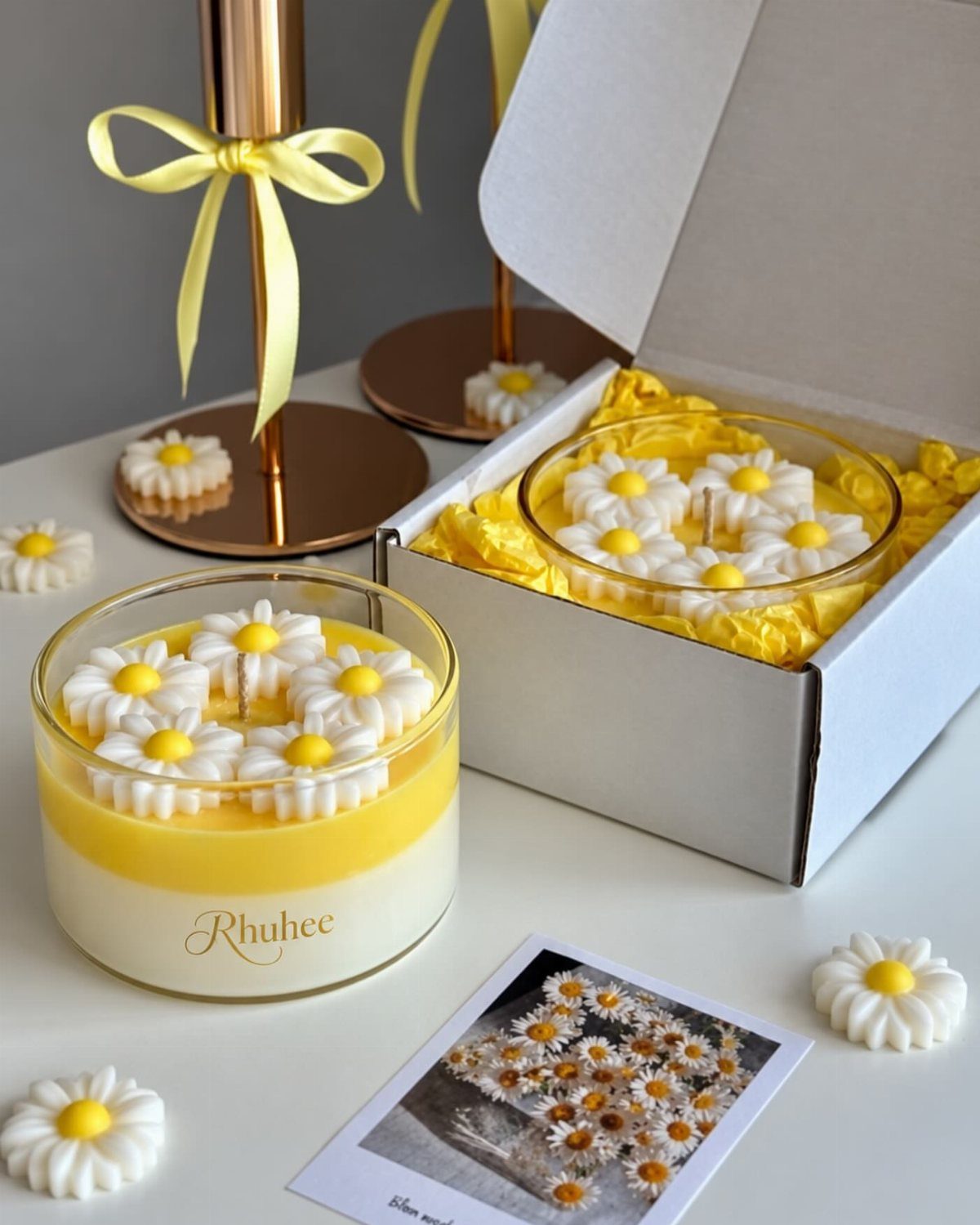 Yellow and white daisy candles in glass jars with a white gift box.