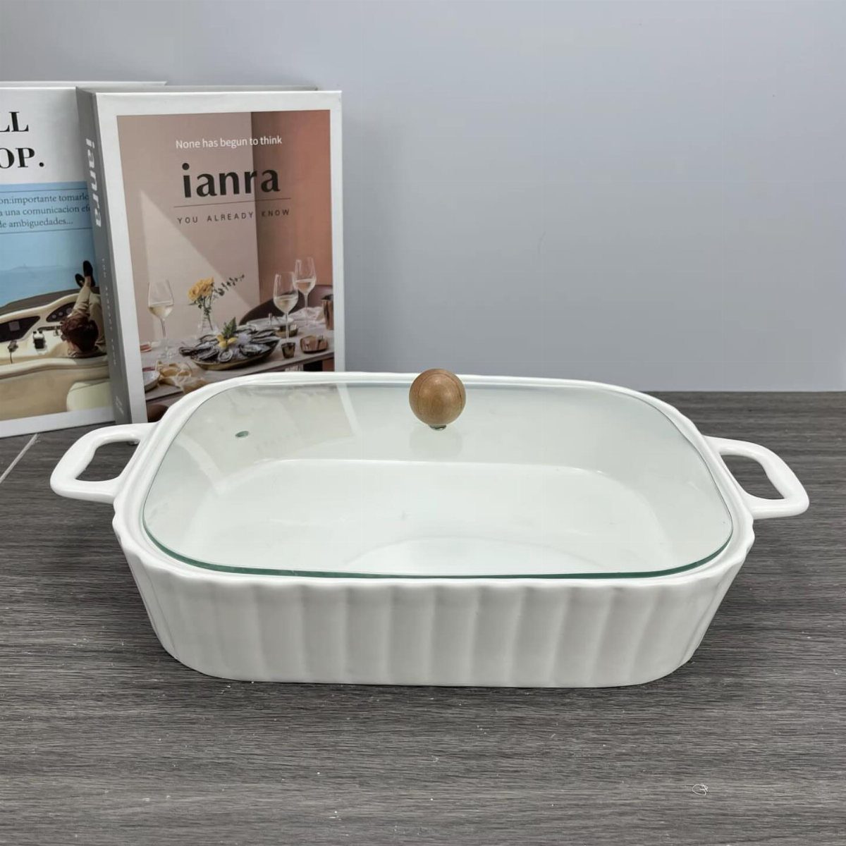 White ceramic fluted baking dish with glass lid on a grey wooden table
