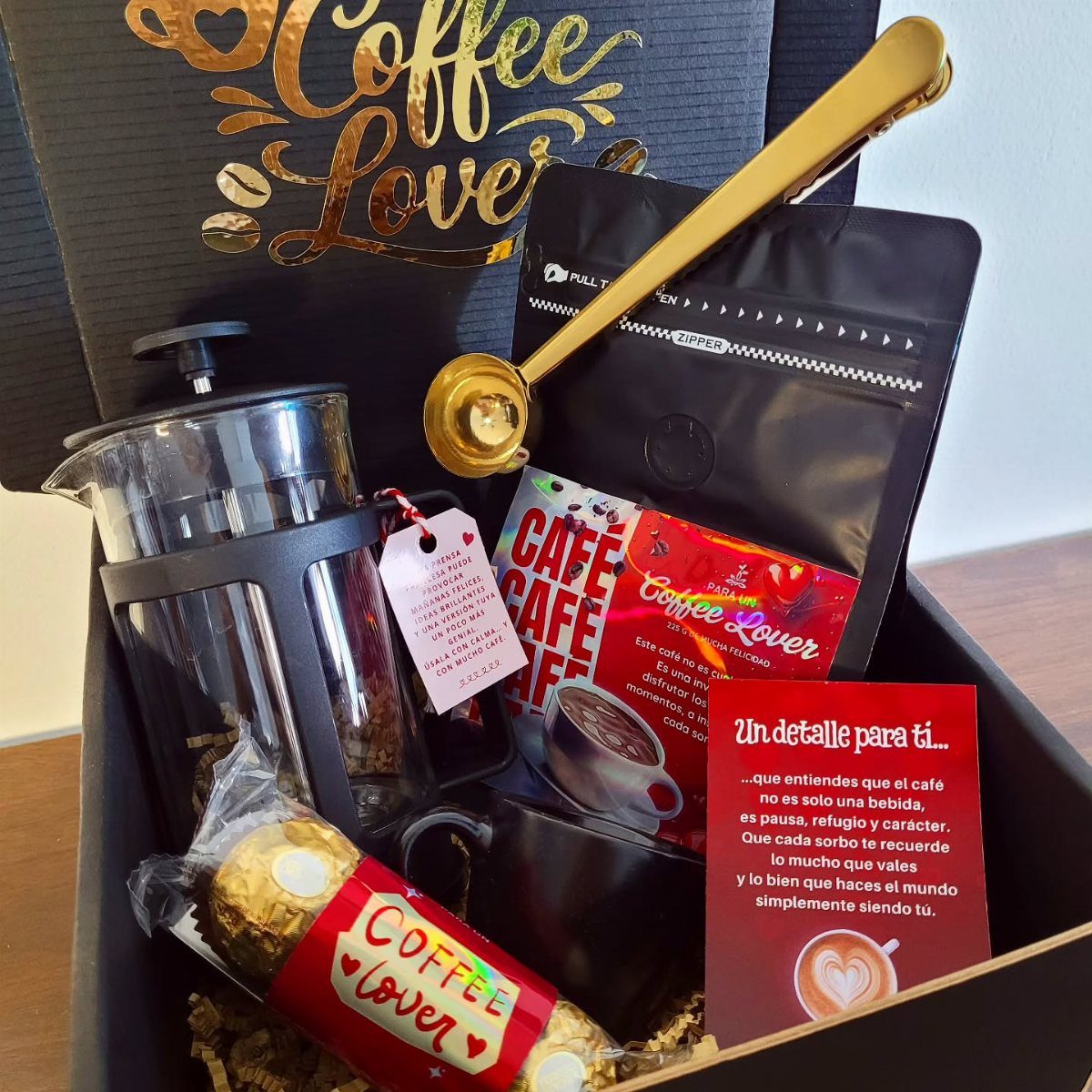 Coffee gift box featuring a glass French press, gold scoop, and coffee beans.