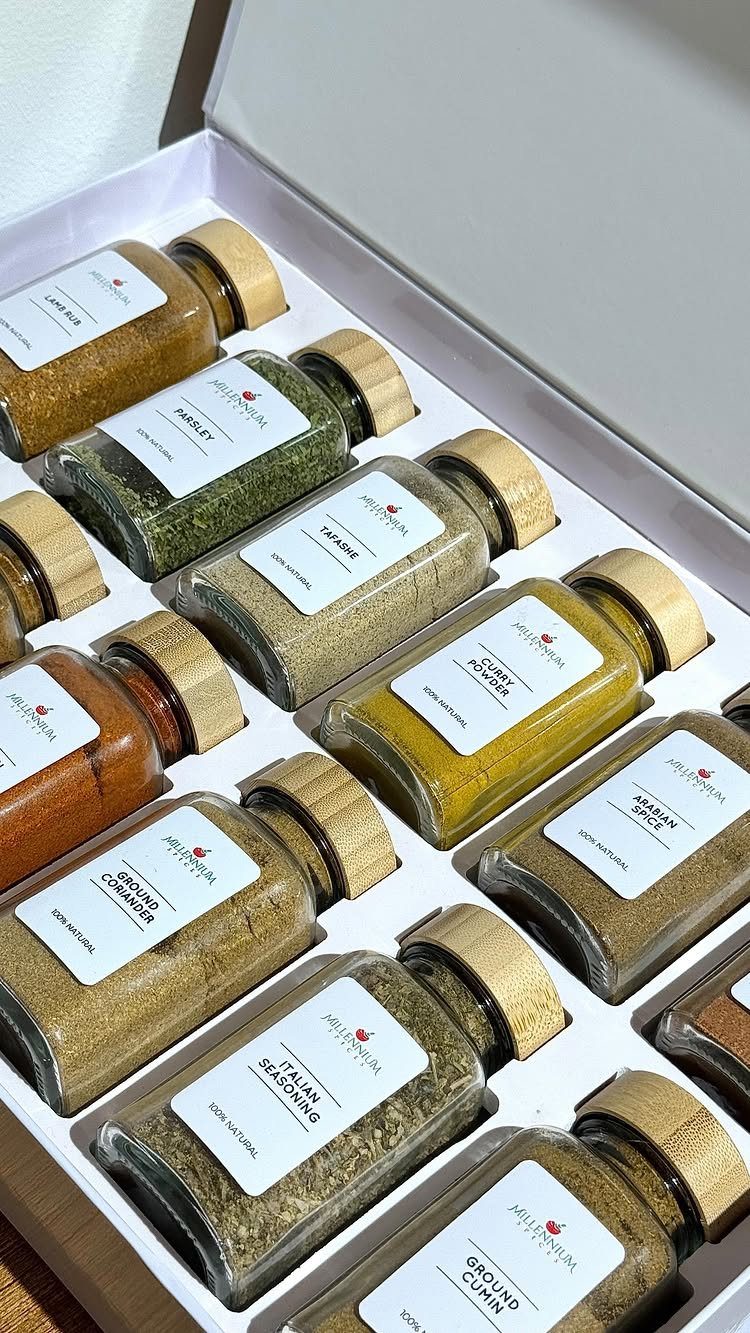 Assorted spice jars with wooden lids arranged in a white gift box.