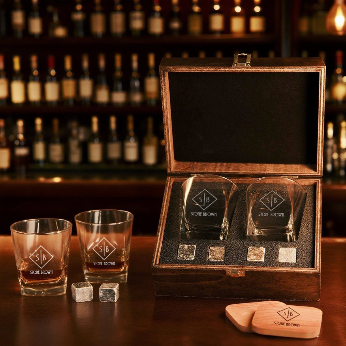 Wooden whiskey gift set with etched glasses and stone cubes on a bar.
