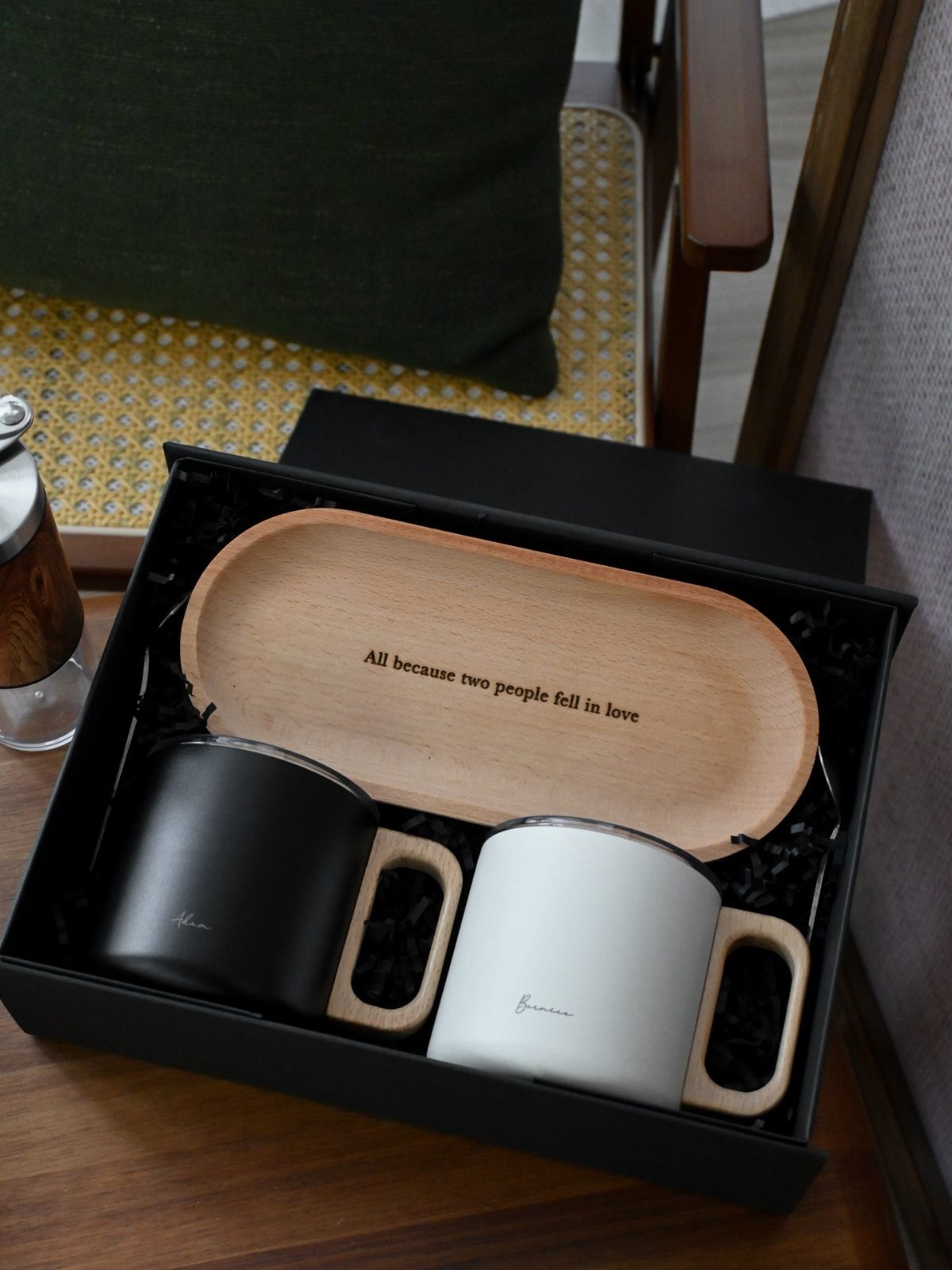 Two ceramic mugs with wooden handles on an engraved wooden tray in a box