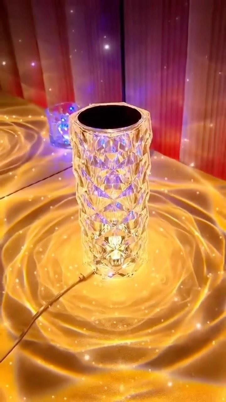 Crystal cylindrical lamp emitting golden light patterns on a flat surface