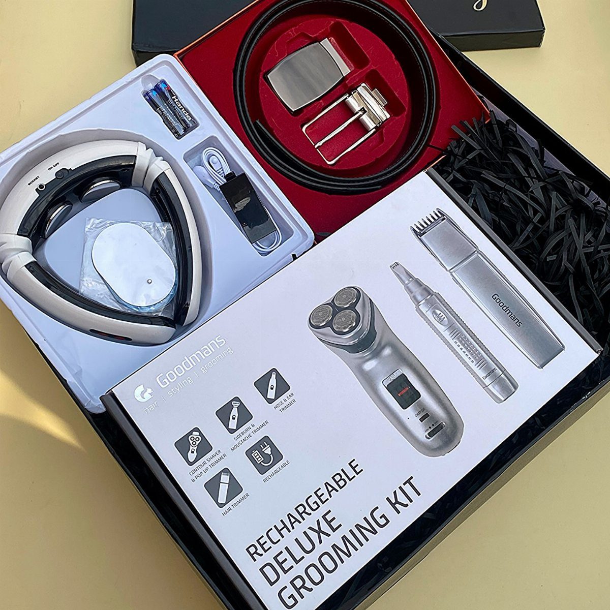 Grooming kit box with electric shavers, headphones, and a leather belt in a gift set.