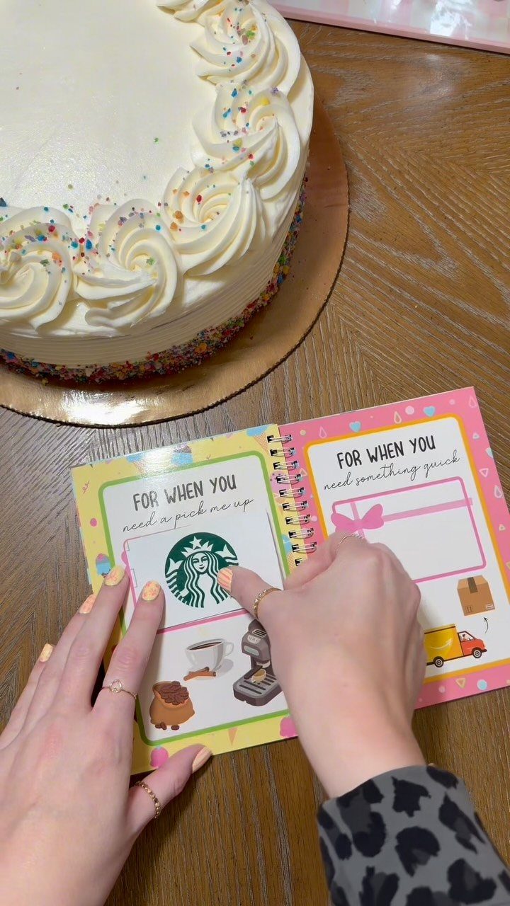 Handmade coupon book with colorful pages and a white frosted cake nearby.
