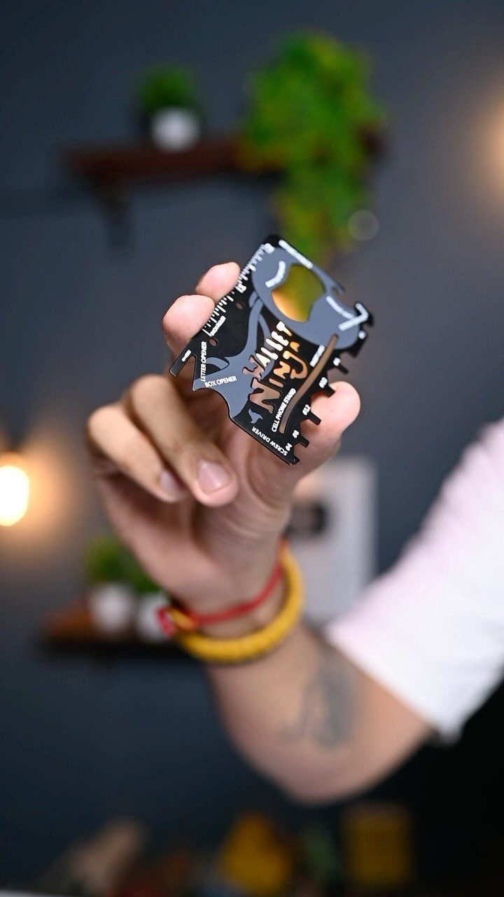 Black metal Wallet Ninja multitool card held in a person's hand indoors.