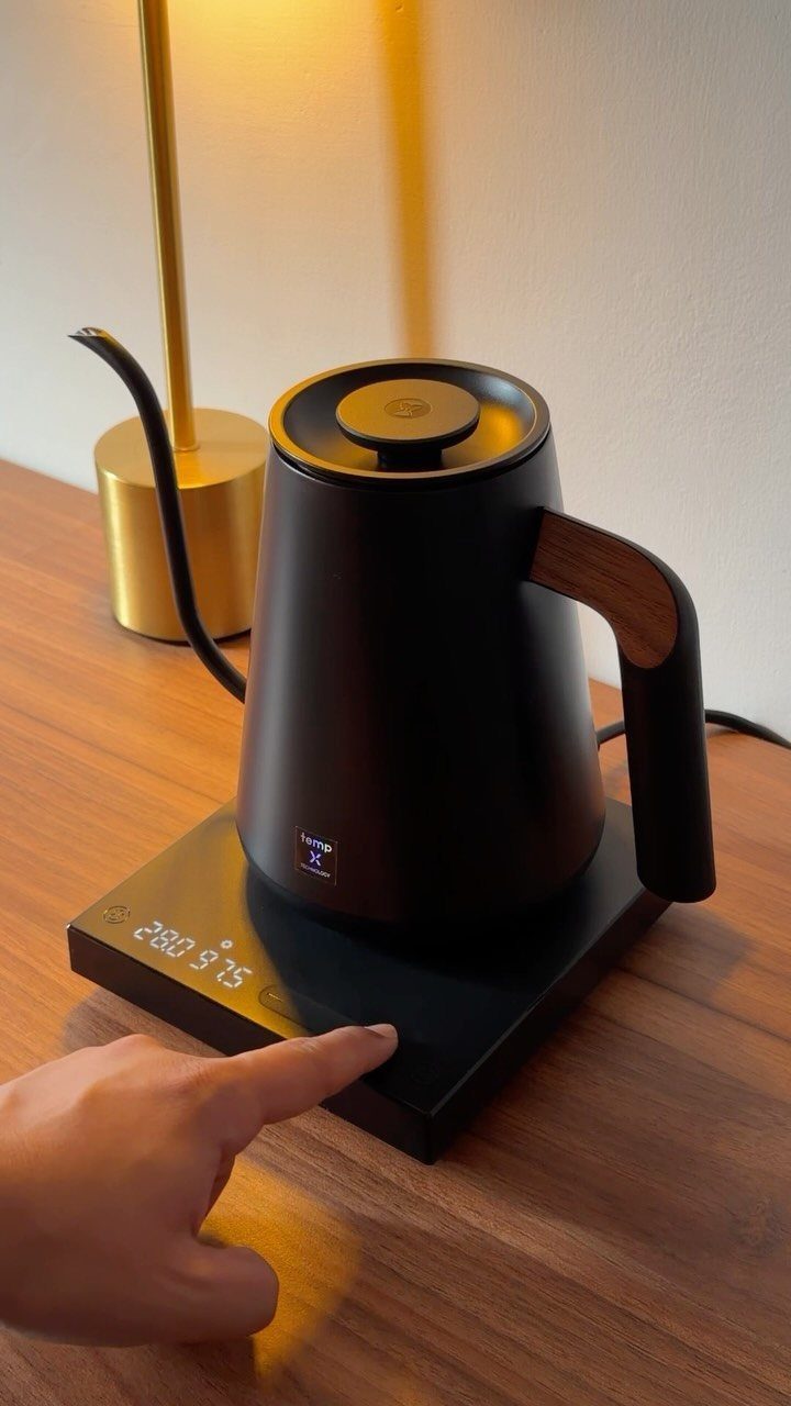 Black electric gooseneck kettle on a digital base on a wooden table