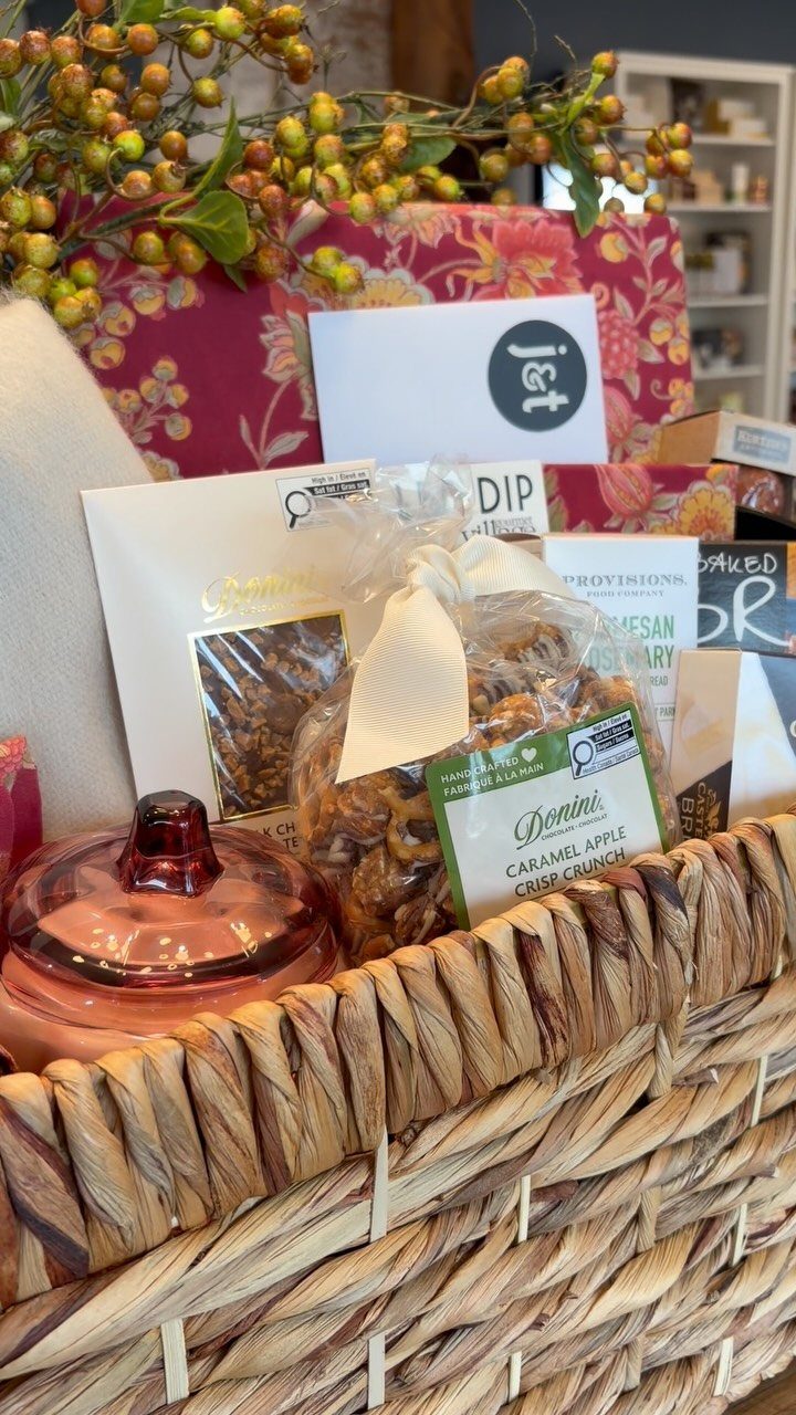 Woven wicker basket filled with gourmet snacks and a small glass jar.
