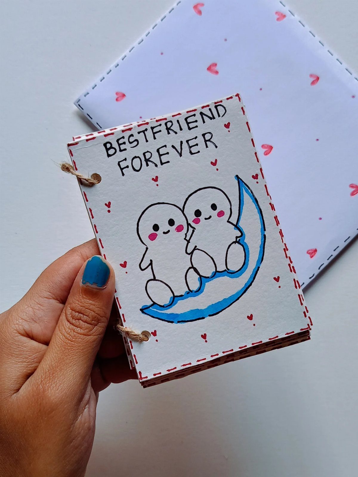 Handmade notebook with cute characters and 'BESTFRIEND FOREVER' text held by a hand.