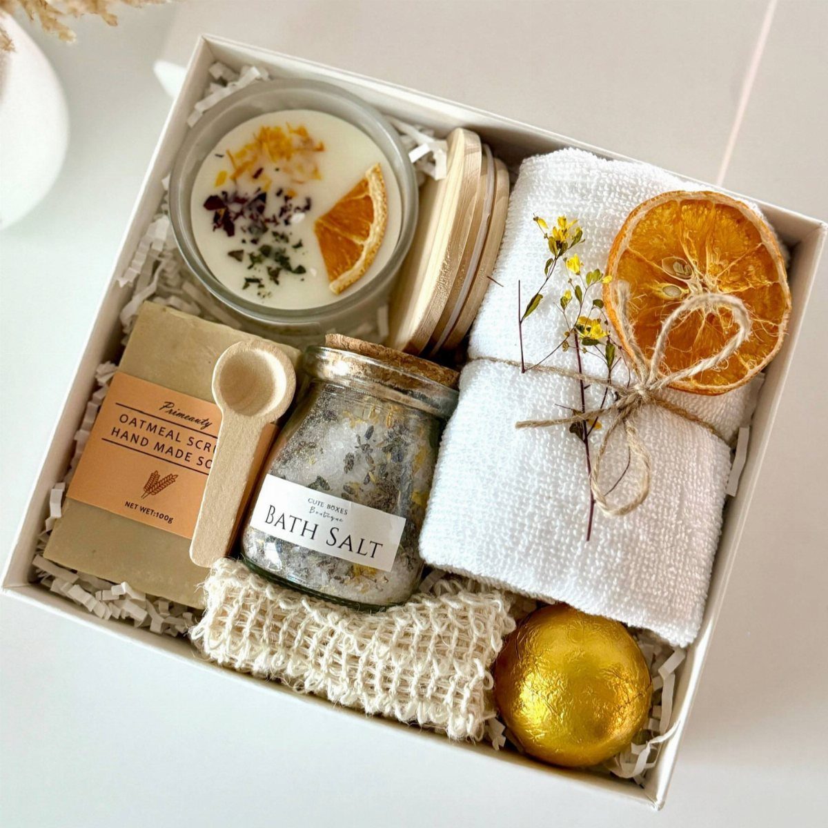 Spa gift box with bath salts, oatmeal scrub, candle, towel, and gold bath bomb.