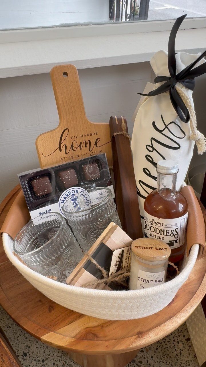 12 Useful Gifts for Men: From Chef's Knives to Multitools 11 Gift basket with wooden board, chocolates, glassware, and gourmet food items on a table.