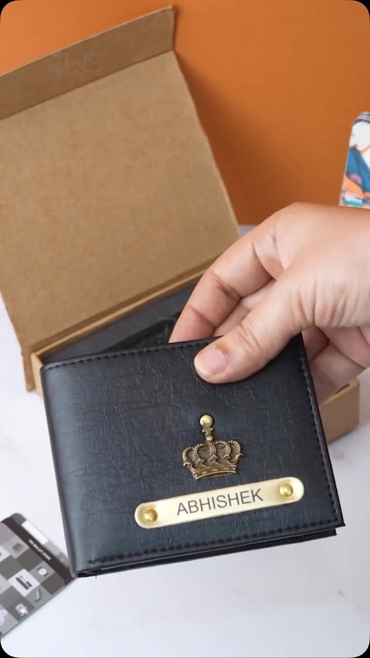 12 Useful Gifts for Men: From Chef's Knives to Multitools 1 Black leather wallet with a gold crown and personalized nameplate held by a hand