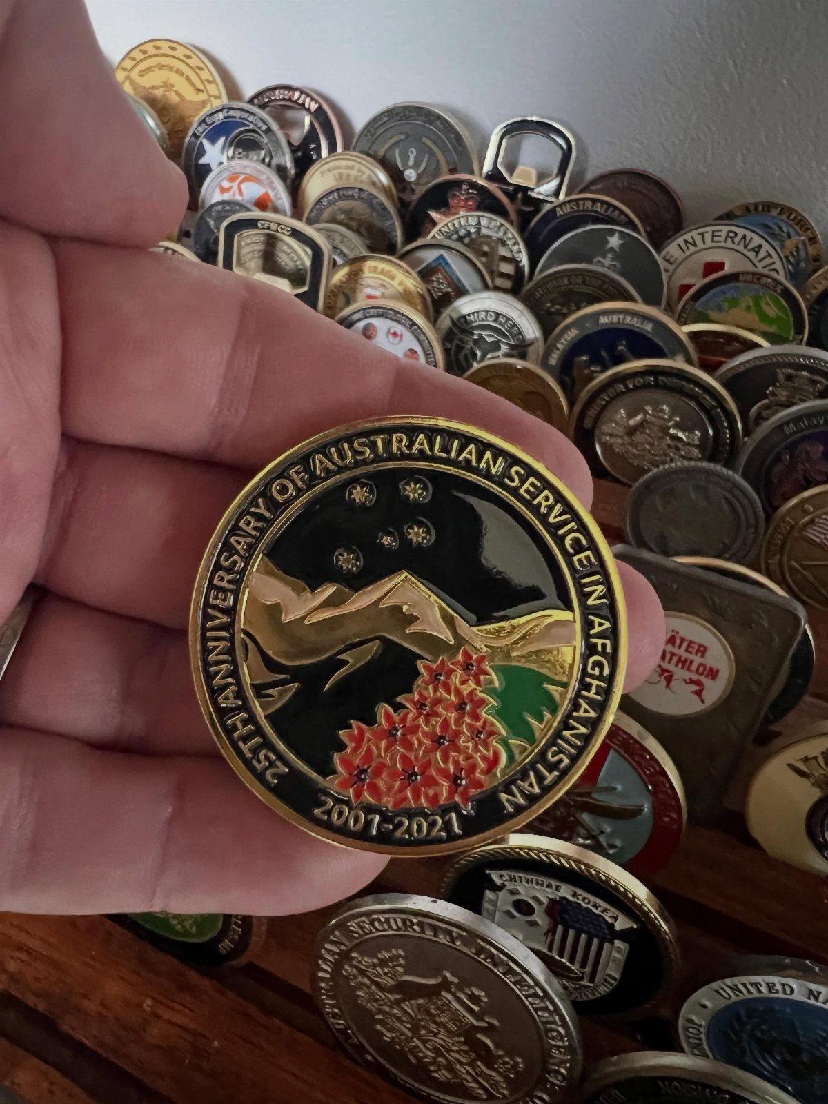 Gold challenge coin for Australian service in Afghanistan held over a collection of coins.