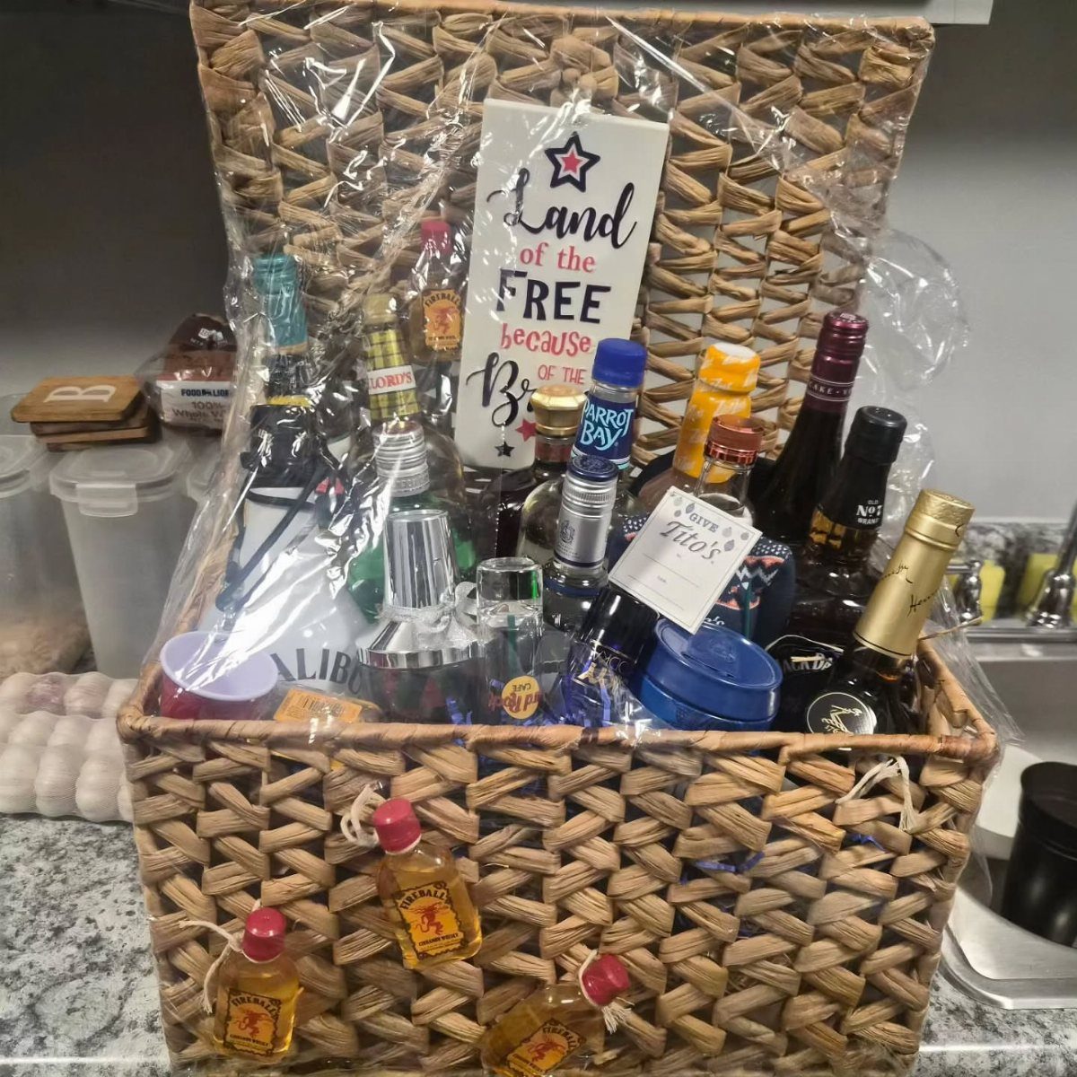 Wicker gift basket with liquor bottles and a patriotic Land of the Free sign.