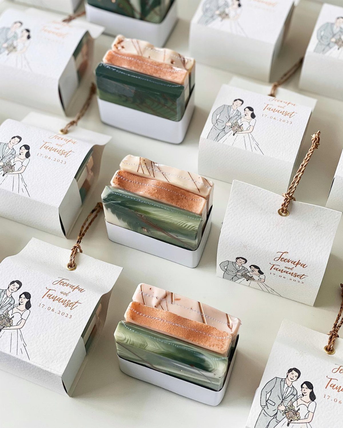 Layered green and peach soaps in white holders with wedding favor tags.