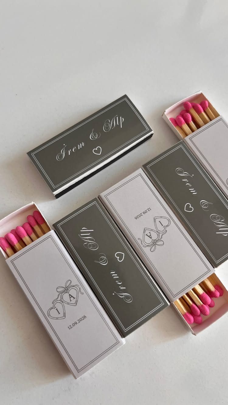 Personalized grey and white matchboxes with pink matches for wedding guest favors.