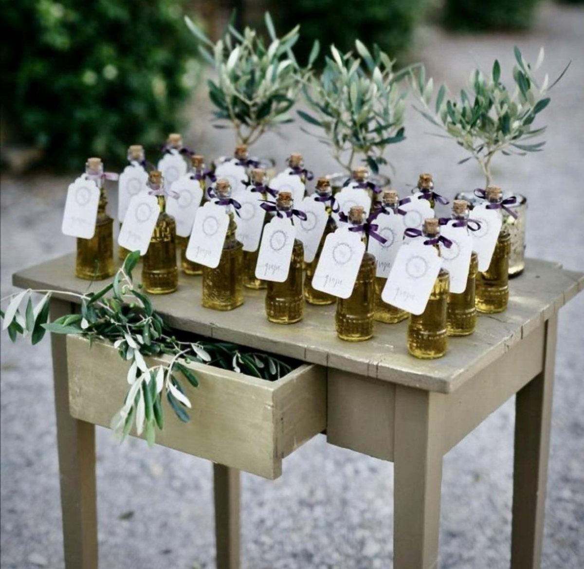 Small bottles of olive oil with purple ribbons on a rustic wooden table.