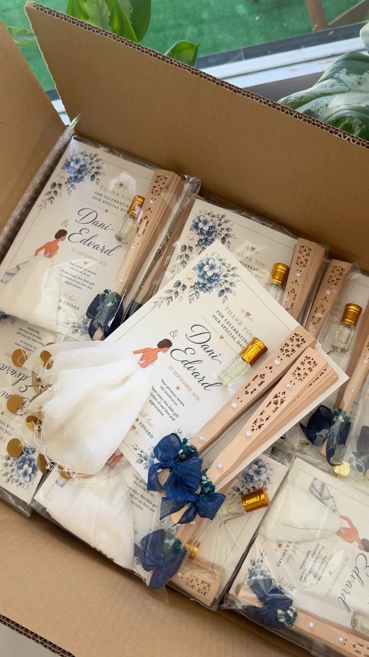 Wedding favor sets with wooden folding fans, perfume vials, and personalized cards.