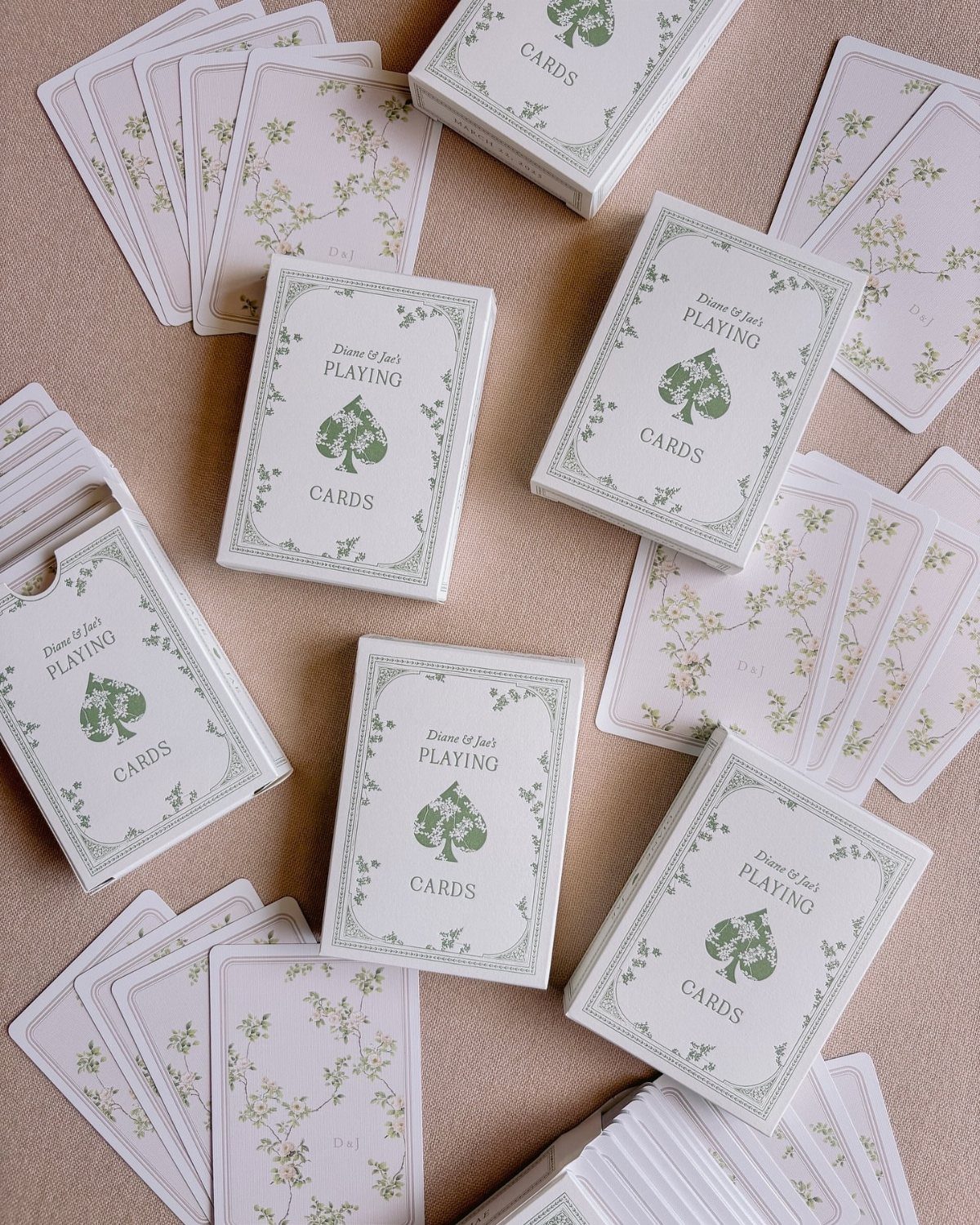 Custom playing cards with green floral designs and spade symbols on beige background