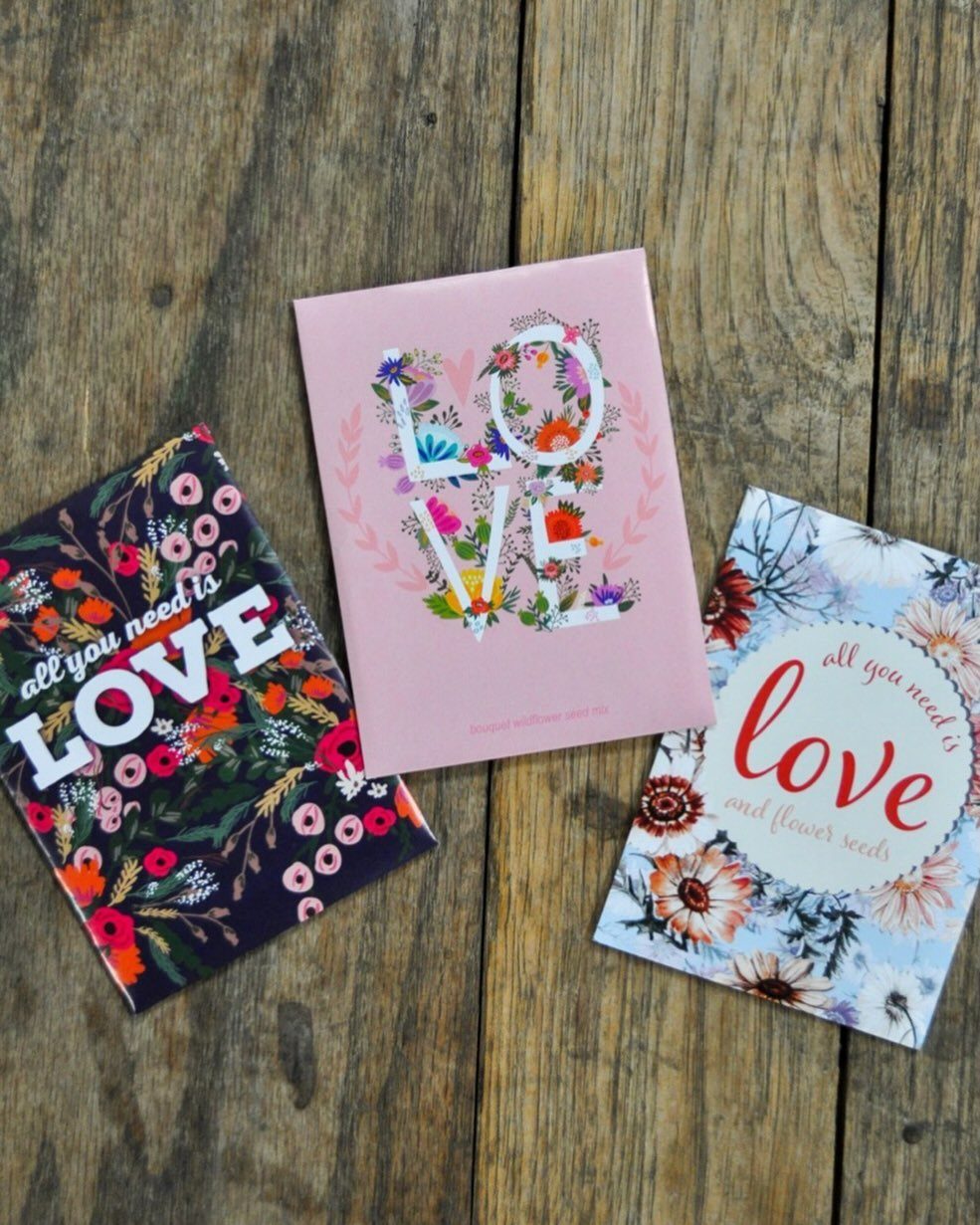 Three floral seed packets with love-themed text on a rustic wooden background.