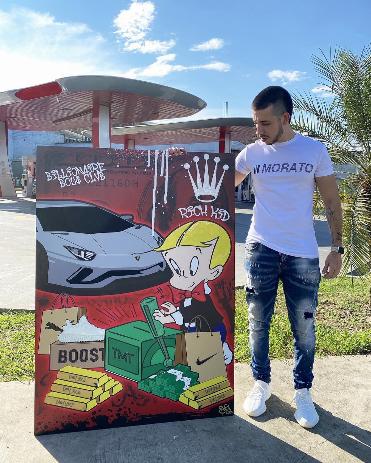 Man standing next to a custom painted portrait featuring a cartoon character and luxury items.