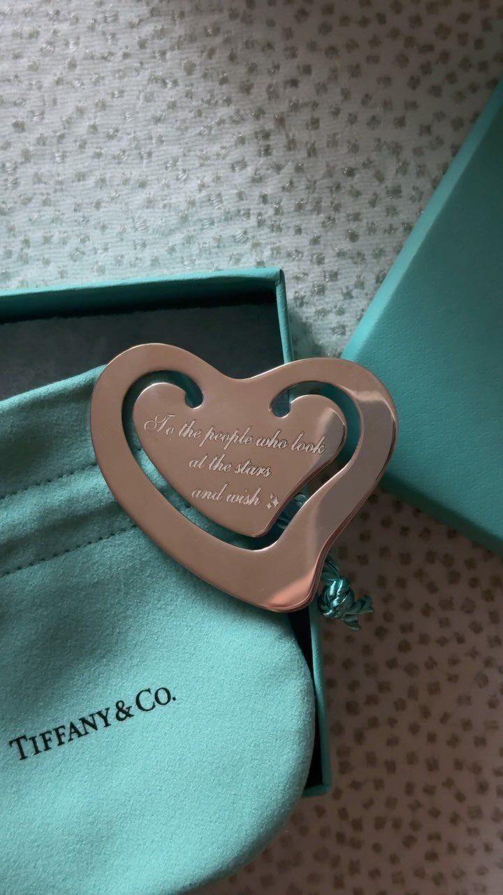 Silver heart-shaped pendant resting on a turquoise Tiffany and Co. jewelry pouch.