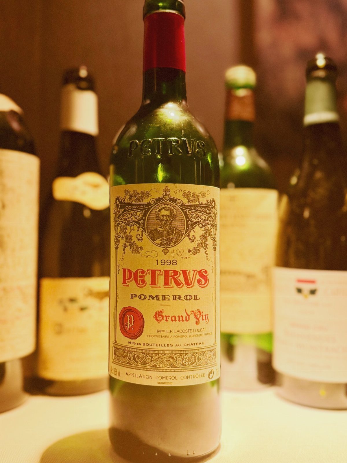 Petrus Pomerol red wine bottle with a detailed label among other wine bottles.
