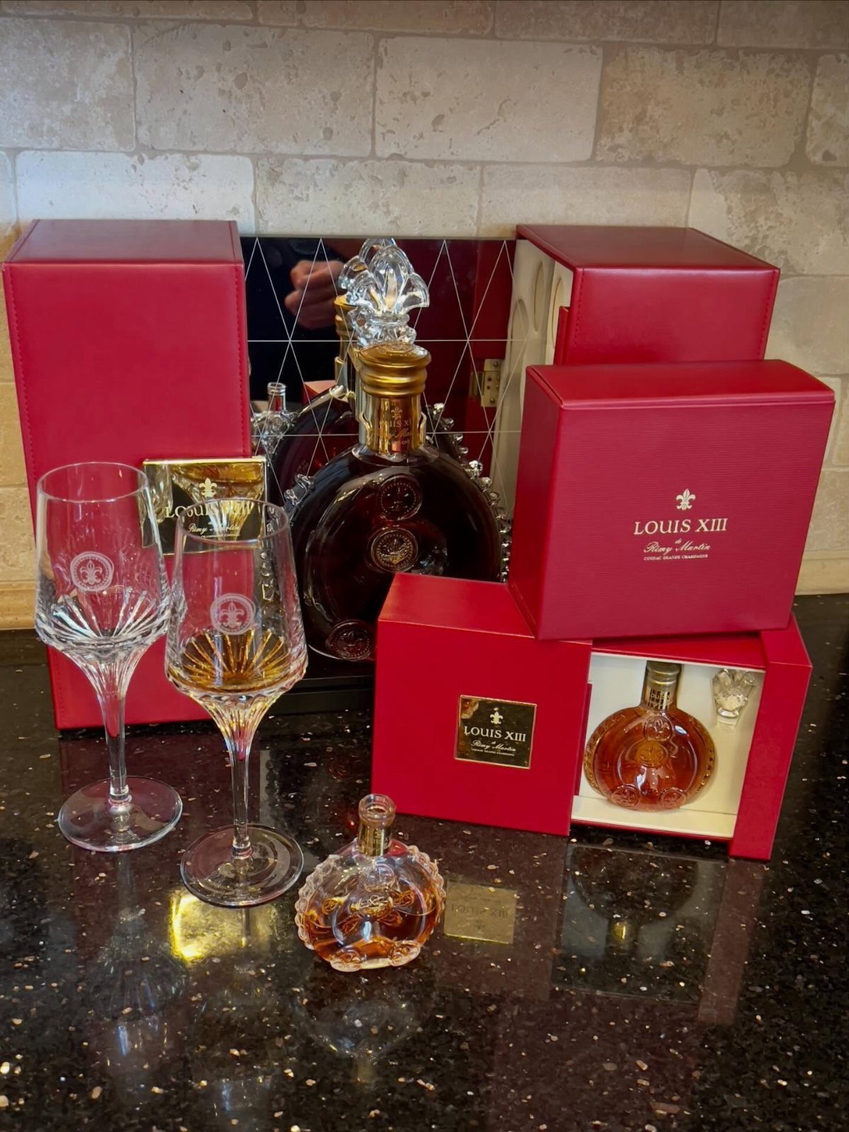 Luxury cognac bottles and crystal glasses with red gift boxes on granite counter