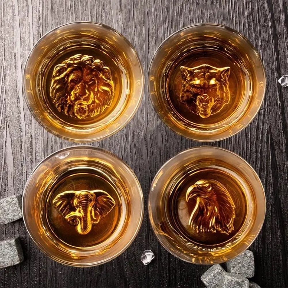 Four glasses of amber liquid with gold animal figures at the bottom.