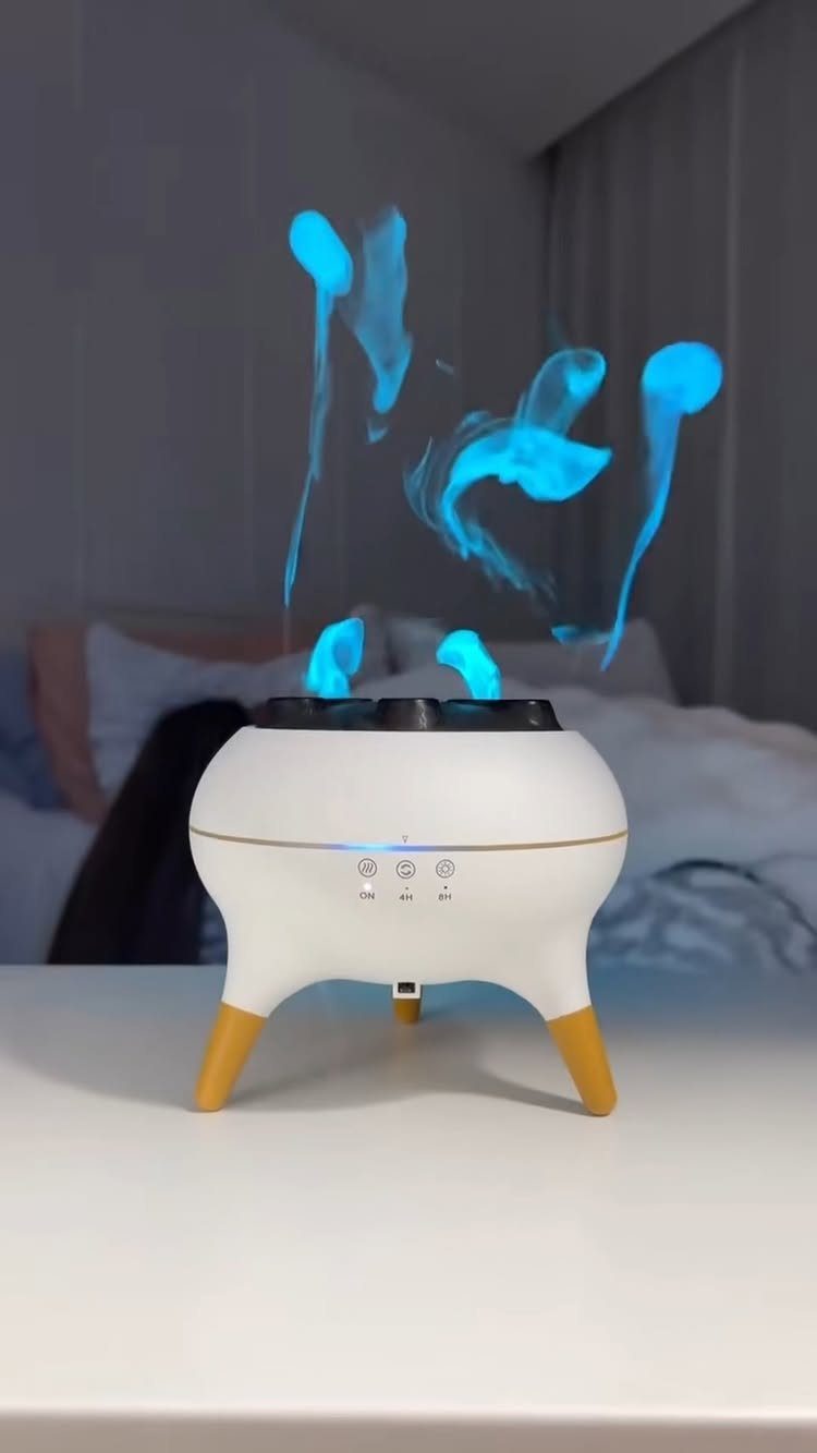 White humidifier with gold legs emitting blue floating water vapor in a bedroom