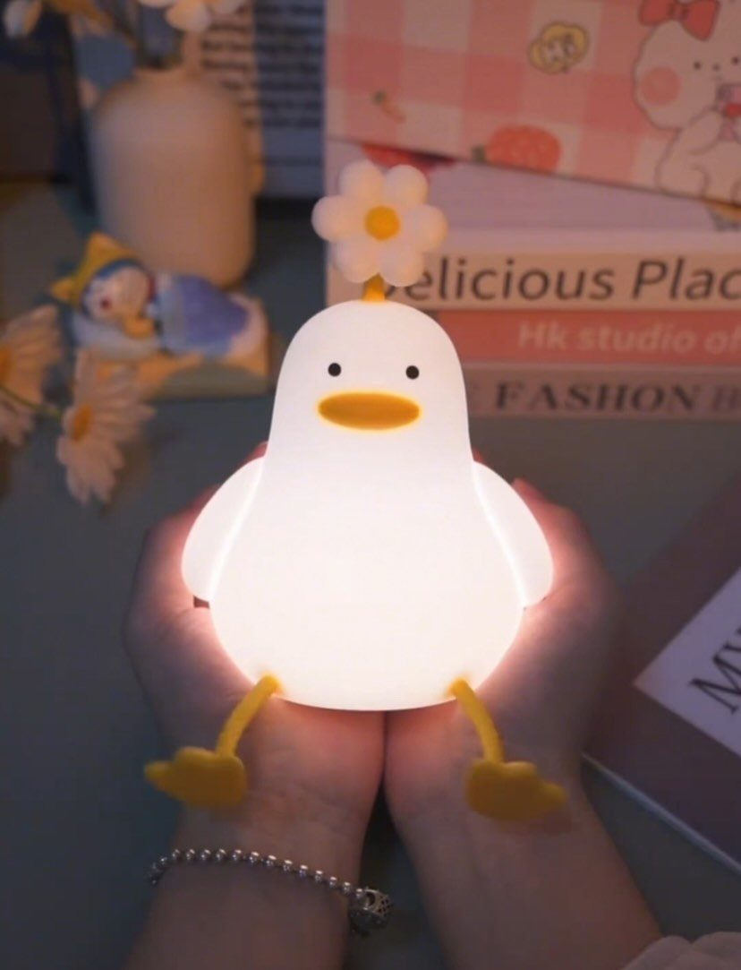Glowing white duck lamp with a flower on its head held in hands