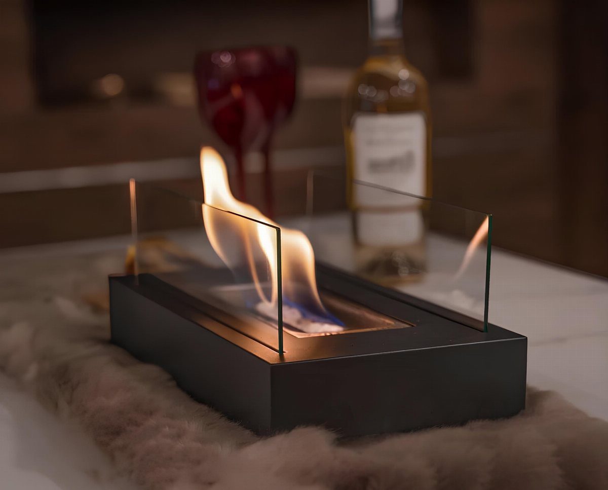 Tabletop glass fireplace with a burning flame on a white fluffy rug