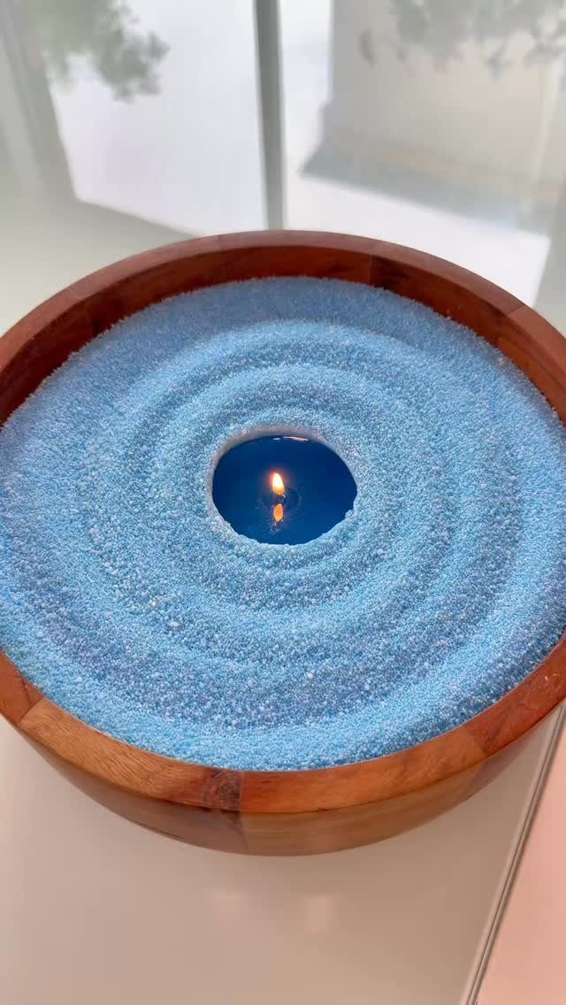 Blue candle in a wooden bowl with raked blue sand Zen garden