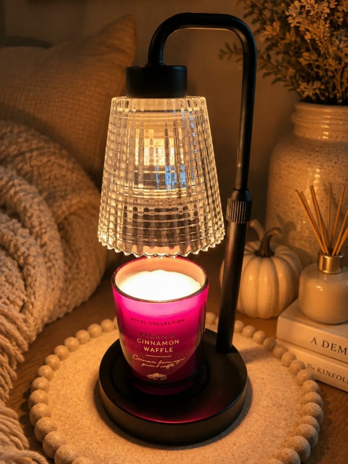 Candle warmer lamp with a ribbed glass shade lighting a pink cinnamon waffle candle.