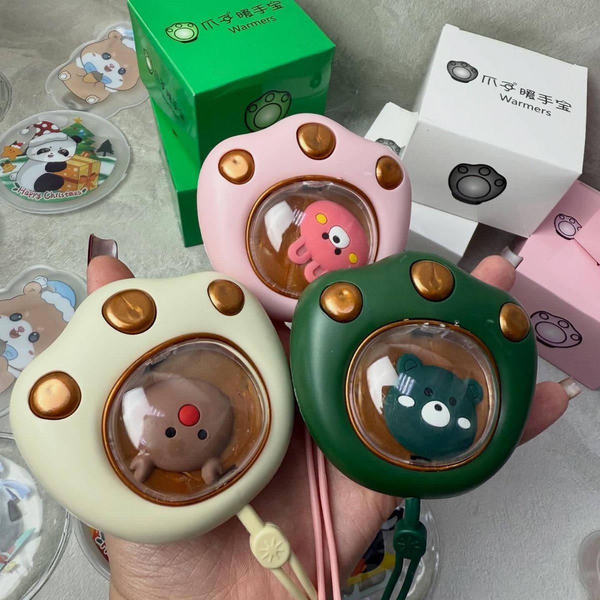 Paw-shaped hand warmers with cute animal figures held in a person's hand.