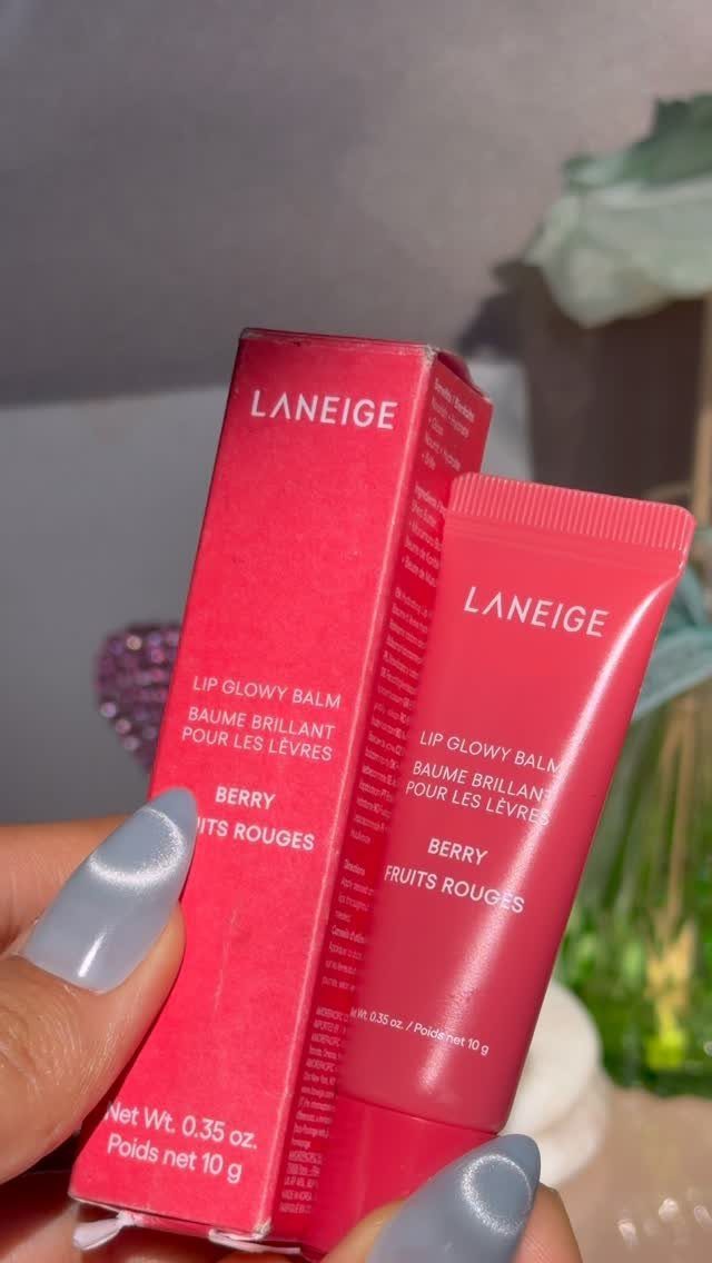 Laneige Lip Glowy Balm tube and pink box held by a hand with blue nails.