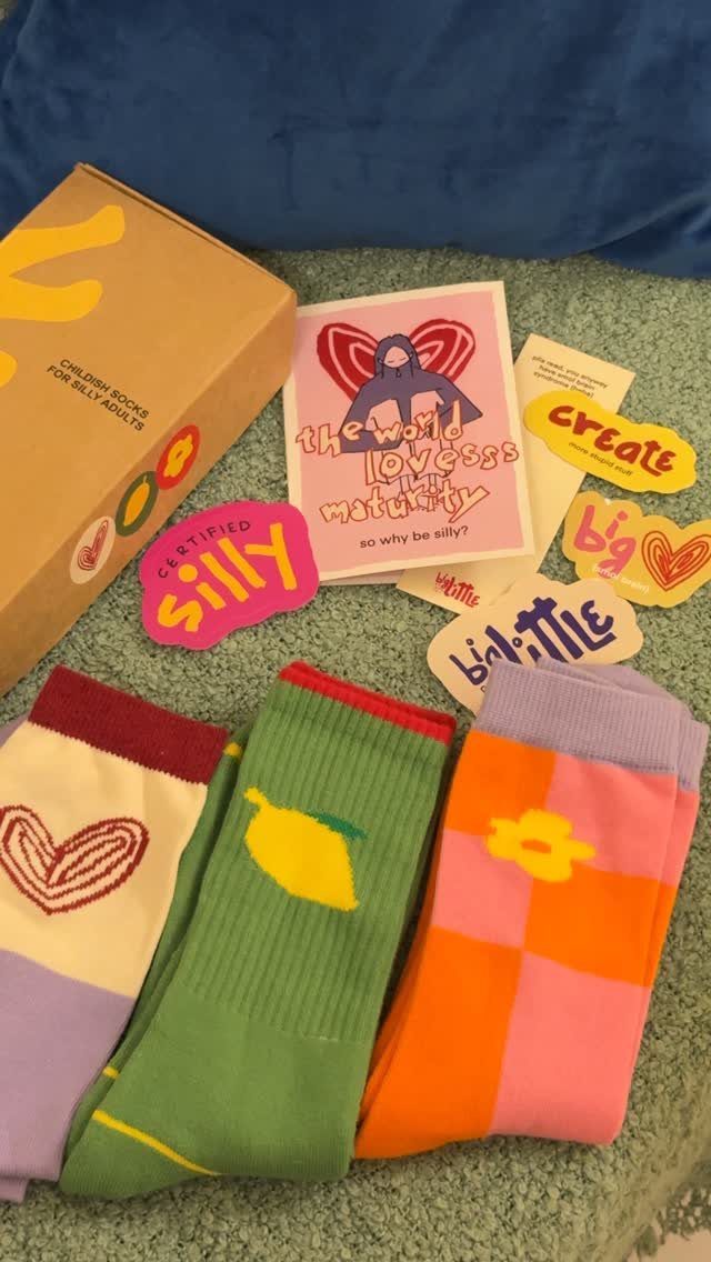 Three pairs of colorful patterned socks with a cardboard box and stickers.