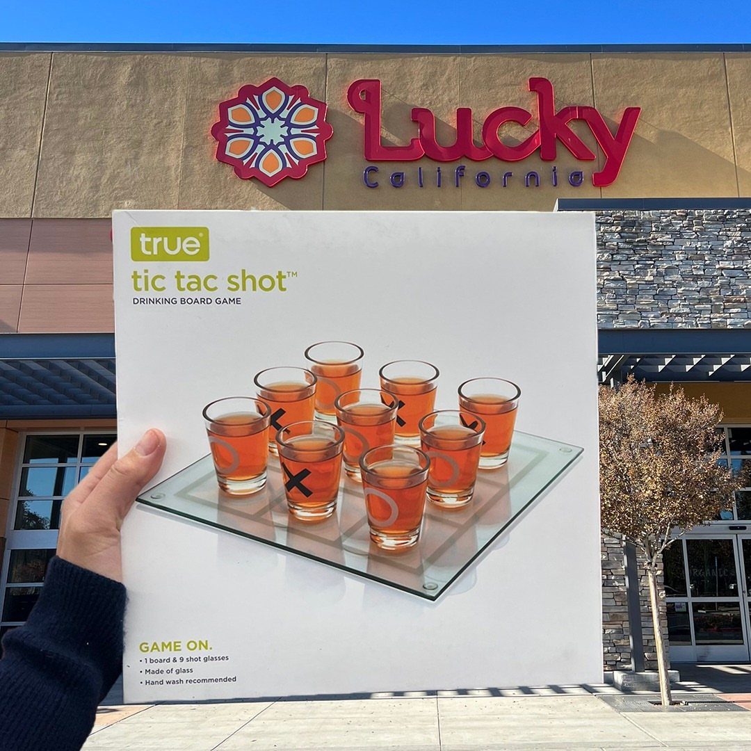 Tic tac shot drinking board game box held in front of a store.