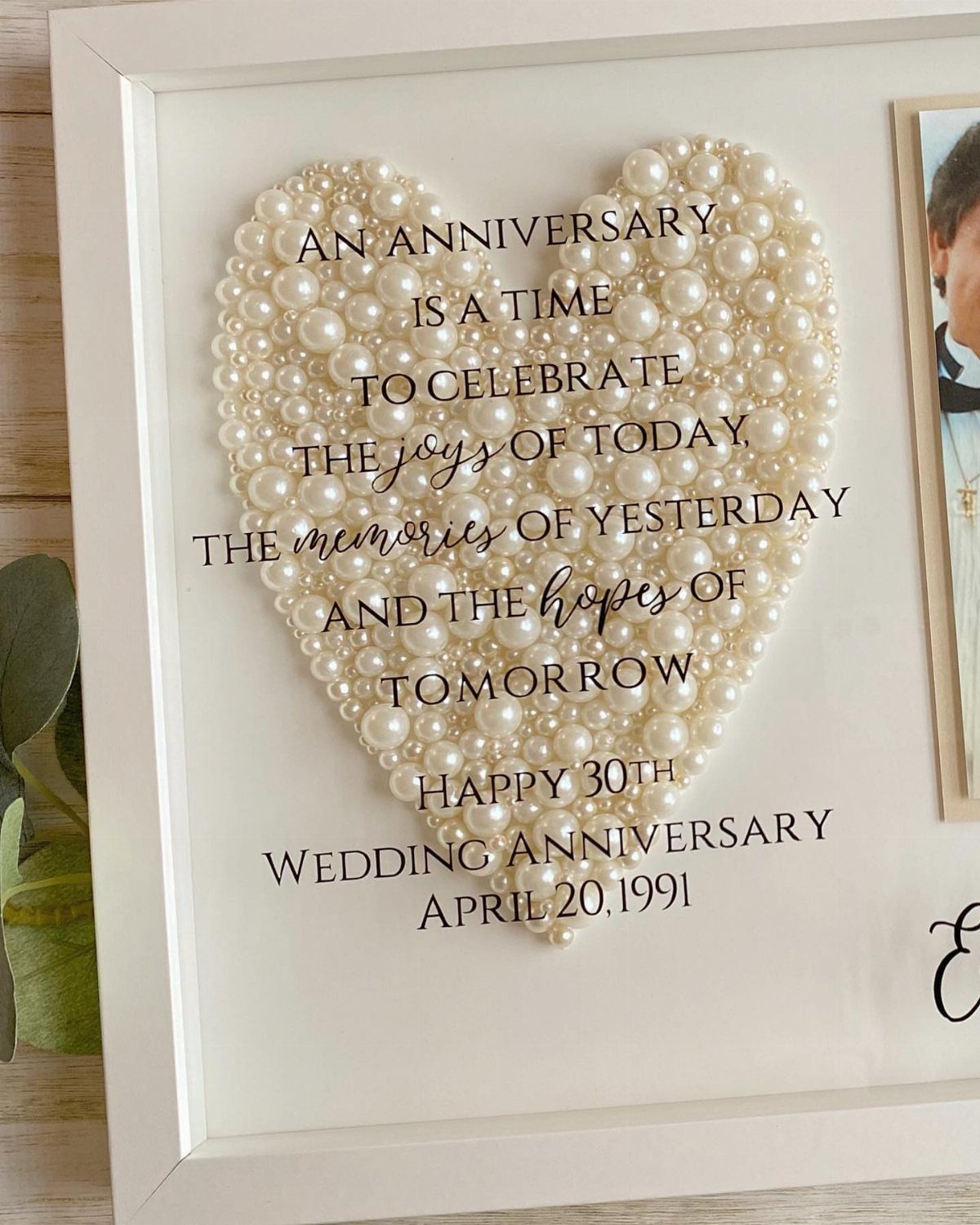 Heart made of white pearls in a white frame with anniversary text.