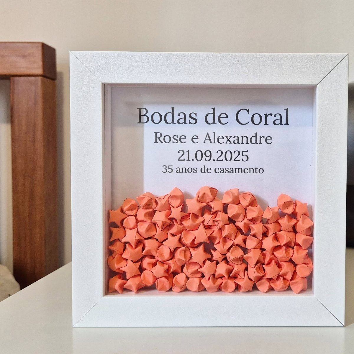 White shadow box frame with orange paper stars and 35th anniversary text.