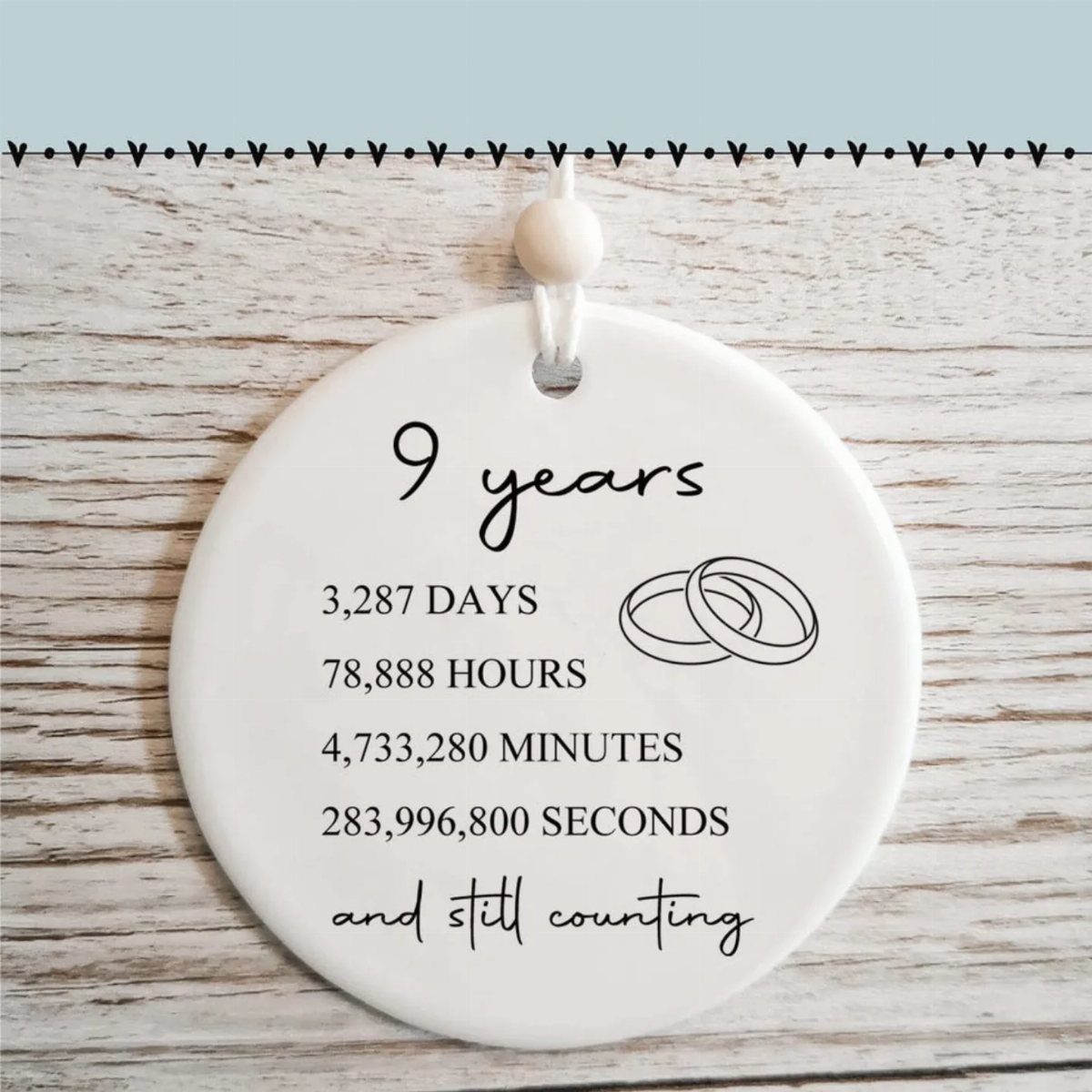 White ceramic anniversary ornament listing time elapsed over nine years with ring illustrations.