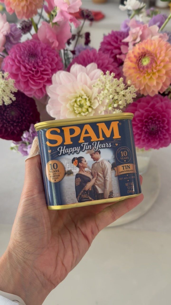 Customized Spam can for a 10th tin anniversary held against colorful flowers
