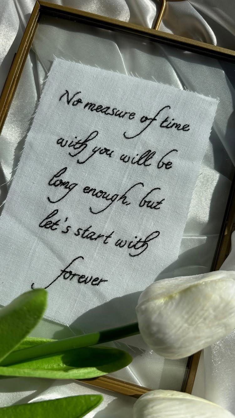 Embroidered romantic quote in a gold frame with white tulips and satin fabric.
